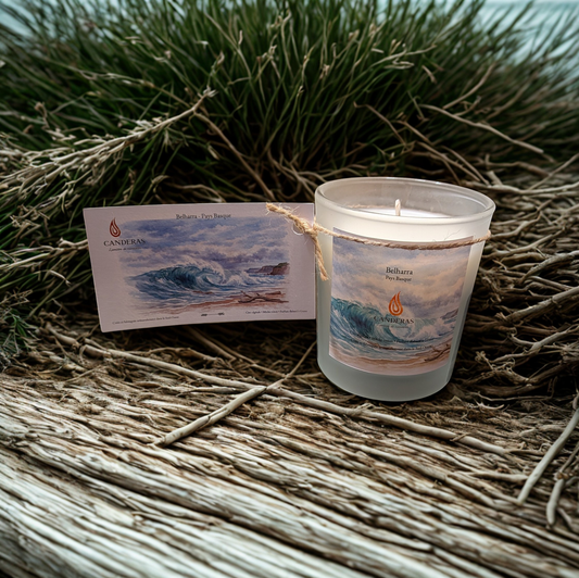 Bougie artisanale du Sud-Ouest Candèras Belharra avec carte postale assortie sur fond bois clair, textile naturel et mur texturé.