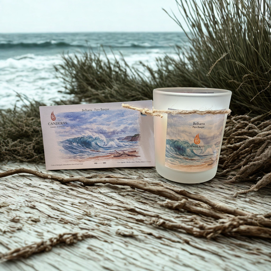 Bougie artisanale du Sud-Ouest Candèras Belharra avec carte postale assortie sur fond bois clair et mur texturé.