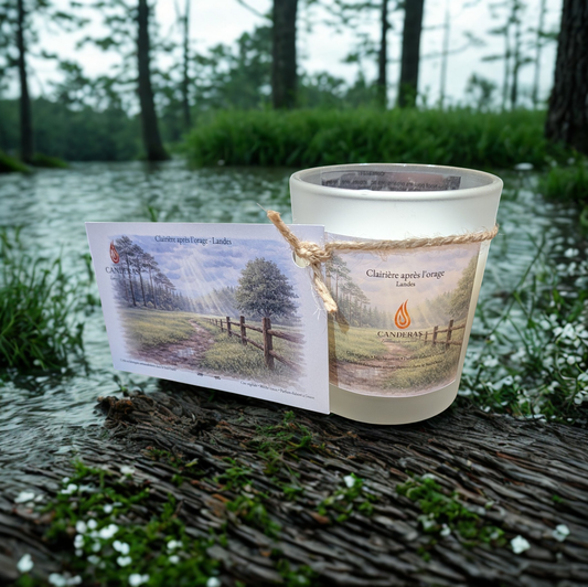 Bougie artisanale du Sud-Ouest Candèras Clairière après l’orage avec carte postale assortie sur fond bois clair et mur texturé.
