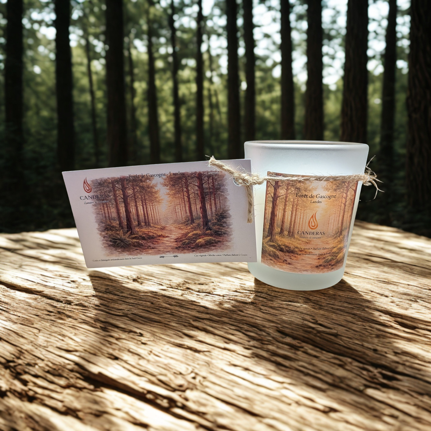 Bougie artisanale du Sud-Ouest Candèras Forêt de Gascogne avec carte postale assortie sur fond bois clair et mur texturé.