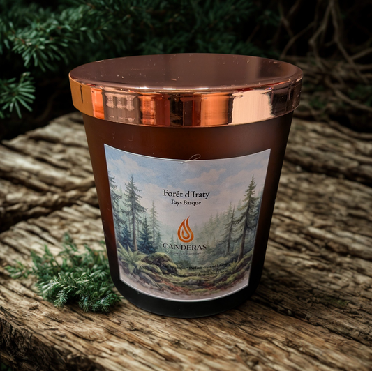 Bougie artisanale du Sud-Ouest Candèras Forêt d’Iraty avec couvercle cuivré sur fond minéral clair.